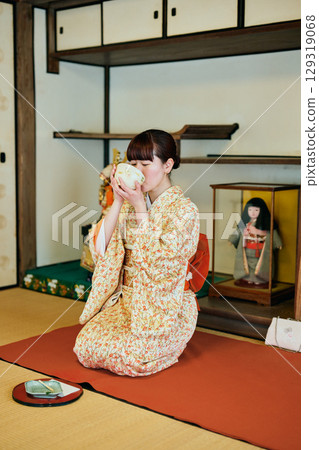 A woman in a kimono enjoying a tea ceremony in a Japanese-style room 129319068