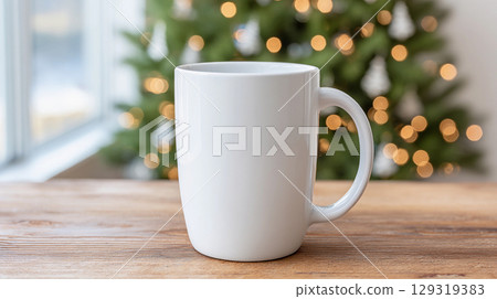 White ceramic mug for mockup placed on a wooden table near a window with soft warm bokeh lights in the background, creating a cozy holiday ambiance 129319383