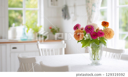Colorful flowers in a glass vase brighten up a cozy kitchen table in a sunlit home during a tranquil afternoon Colorful flowers in a glass vase brighten up a cozy kitchen table in a sunlit home during a tranquil afternoon 129319392