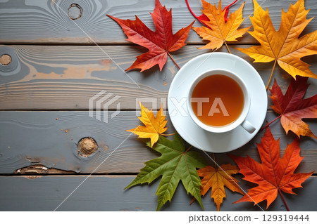 Cup of tea on a wooden table surrounded by autumn leaves. 129319444