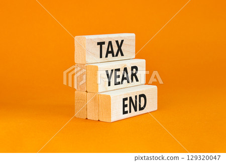 Tax year end symbol. Concept words Tax year end on beautiful wooden blocks. Beautiful orange table orange background. Business tax year end concept. Copy space. Tax year end symbol. Concept words Tax year end on beautiful wooden blocks. Beautiful orange table orange background. Business tax year end concept. Copy space. 129320047