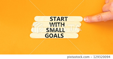 Start with small goals symbol. Concept words phrase Start with small goals on beautiful stick. Businessman's hand. Beautiful orange background. Business Start with small goals concept. Copy space. 129320094