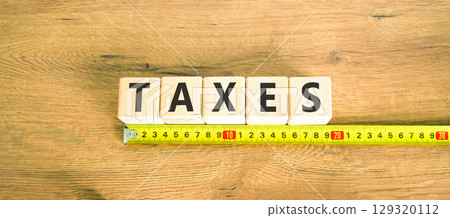 Taxes symbol. Concept word Taxes on beautiful wooden blocks. Beautiful wooden table wooden background. Beautiful yellow ruler. Business lifestyle taxes concept. Copy space. 129320112