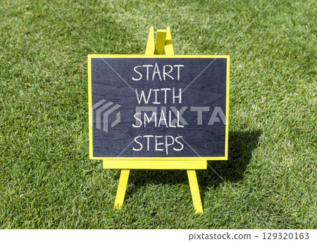 Start with small steps symbol. Concept words phrase Start with small steps on beautiful black blackboard. Beautiful green grass lawn background. Business Start with small steps concept. Copy space. Start with small steps symbol. Concept words phrase Start with small steps on beautiful black blackboard. Beautiful green grass lawn background. Business Start with small steps concept. Copy space. 129320163