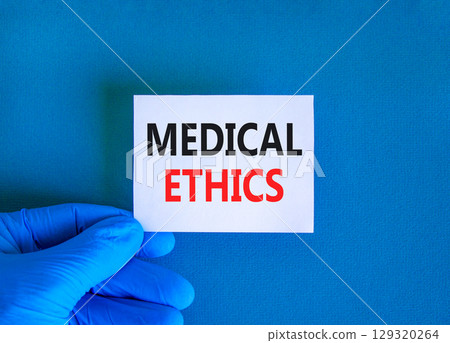 Medical ethics symbol. Concept words Medical ethics on beautiful white card. Doctor's hand in blue glove. Beautiful blue background. Medical healthy lifestyle medical ethics concept. 129320264