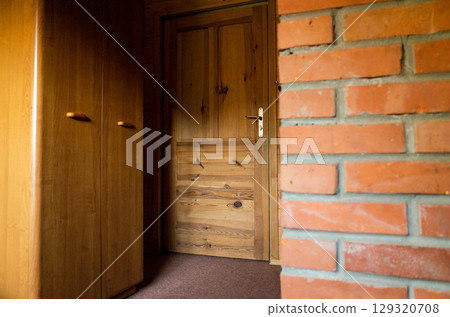 Room with a wooden door and a brick wall 129320708