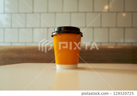 Coffee cup with a lid sits on a table Coffee cup with a lid sits on a table 129320725