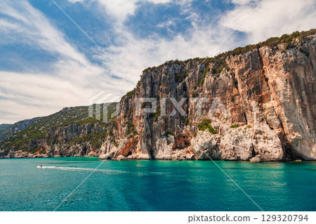 Steep limestone cliffs and clear turquoise sea on Sardinian Gulf of Orosei 129320794
