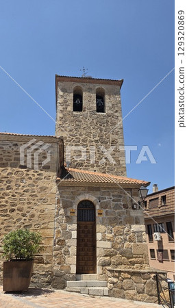 Historic spanish church with stone facade under clear blue sky. Iglesia San Miguel Arcangel de Pedrezuela. Church of Saint Michael the Archangel in Pedrezuela, Spain Historic spanish church with stone facade under clear blue sky. Iglesia San Miguel Arcangel de Pedrezuela. Church of Saint Michael the Archangel in Pedrezuela, Spain 129320869