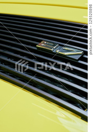 Yellow car with a black grill and a silver numbers 2.7 on it. Phone wallpapers. Vertical background. Yellow car with a black grill and a silver numbers 2.7 on it. Phone wallpapers. Vertical background. 129320898