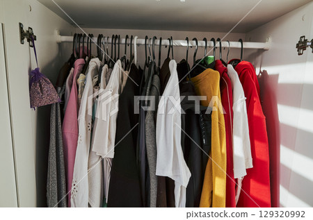 Closet full of clothes with a white shirt hanging on the left side Closet full of clothes with a white shirt hanging on the left side 129320992