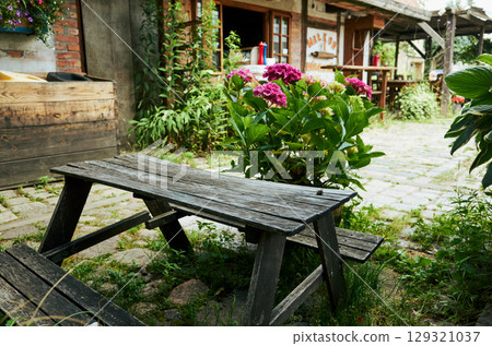 Wooden picnic table sits in front of a flower garden Wooden picnic table sits in front of a flower garden 129321037