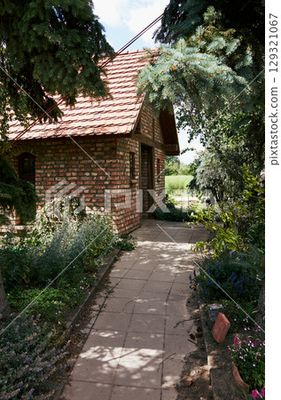 Brick house with a red roof and a path leading to it 129321067