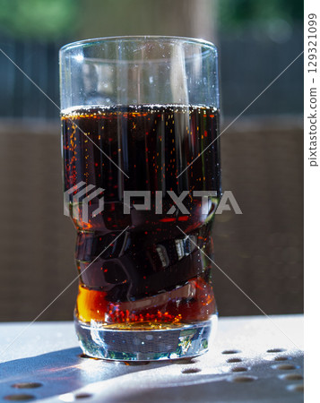 Glass of dark soda sits on a table Glass of dark soda sits on a table 129321099