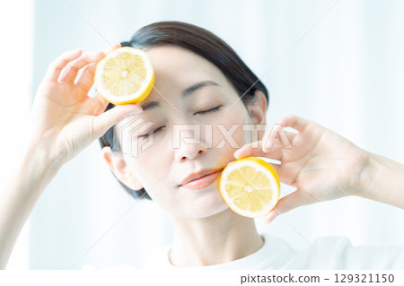 燈光下，一位透明女子雙手捧著檸檬。臉部特寫。 129321150
