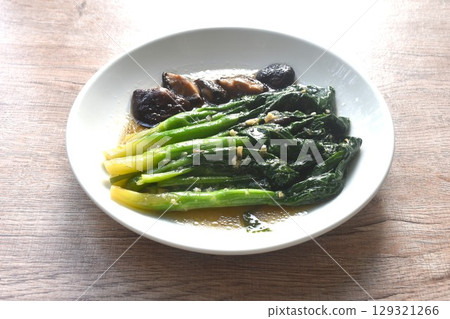 fried Kailaan Chinese kale and black mushroom dressing oyster sauce with chop garlic on plate 129321266