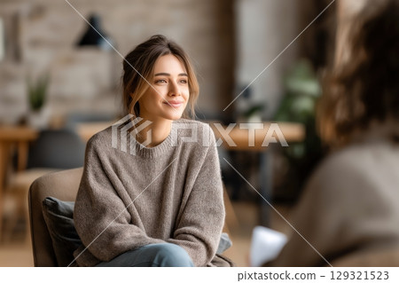 Smiling young woman in therapy session, seeking mental wellness support in a modern office 129321523