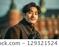 Stylish asian man traveling and photographing european city with camera outdoors 129321524