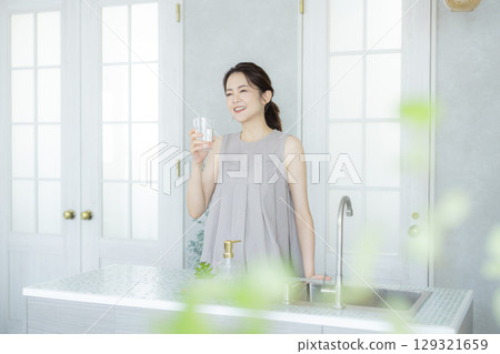 Middle-aged woman drinking water in the kitchen 129321659