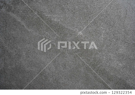A close-up of a textured dark gray stone surface with subtle natural patterns and lines A close-up of a textured dark gray stone surface with subtle natural patterns and lines 129322354
