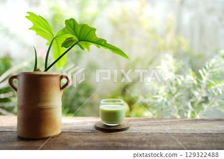Matcha in a glass cup with potted plant on rustic wooden table 129322488