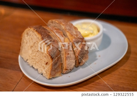 Sliced bread with butter served on plate, on the table in the restaurant Sliced bread with butter served on plate, on the table in the restaurant 129322555