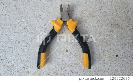 Essential hand tool for cutting wires and cables with ergonomic grip on stone surface. Wire cutters or diagonal cutting pliers Essential hand tool for cutting wires and cables with ergonomic grip on stone surface. Wire cutters or diagonal cutting pliers 129322625