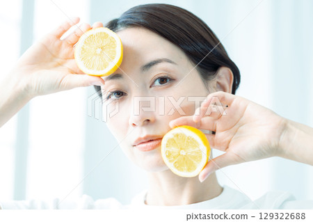 燈光下，一位透明女子雙手捧著檸檬。臉部特寫。 129322688