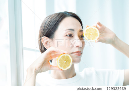 燈光下,一位透明女子雙手捧著檸檬。臉部特寫。 燈光下,一位透明女子雙手捧著檸檬。臉部特寫。 129322689