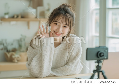 Young asian woman creating content for social media with her camera in bright room 129322730