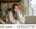 Young woman enjoying a peaceful moment with coffee and laptop in a cozy cafe setting 129322735