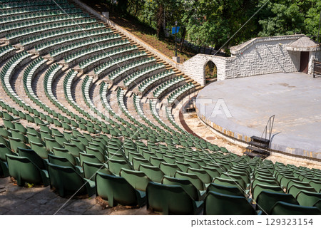 Amphitheater with concentric rows of tiered seating curving around a central stage area under an open sky Amphitheater with concentric rows of tiered seating curving around a central stage area under an open sky 129323154