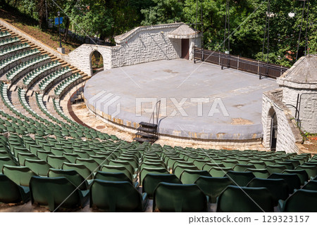 Amphitheater with concentric rows of tiered seating curving around a central stage area under an open sky Amphitheater with concentric rows of tiered seating curving around a central stage area under an open sky 129323157