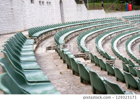 Large, open-air stone amphitheater is filled with numerous rows of green plastic seats arranged in a semi-circular pattern Large, open-air stone amphitheater is filled with numerous rows of green plastic seats arranged in a semi-circular pattern 129323171