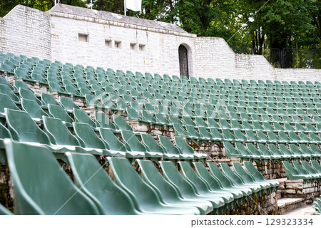 Large, open-air stone amphitheater is filled with numerous rows of green plastic seats arranged in a semi-circular pattern 129323334