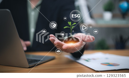 Sustainability, green investment, and responsible business growth. Professional hand holding glowing plant with digital ESG icons like globe, recycling, and carbon emissions. 129323565