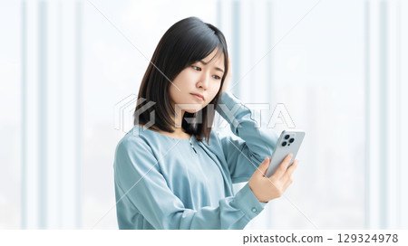 女人/女商人一邊看著智慧型手機一邊思考 女人/女商人一邊看著智慧型手機一邊思考 129324978