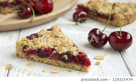 slice of cherry pie with crumble topping and fresh cherries on the table 129325474