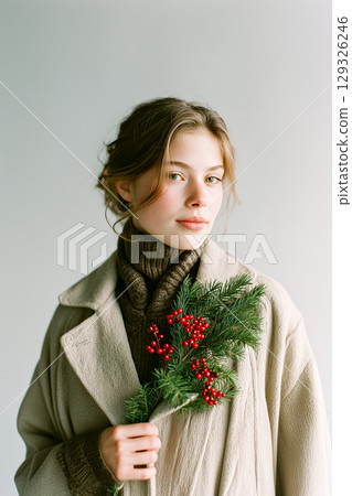 A woman is holding a Christmas wreath in her hand 129326246