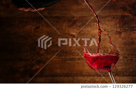Red wine splashing into a glass with a rustic wooden background Red wine splashing into a glass with a rustic wooden background 129326277