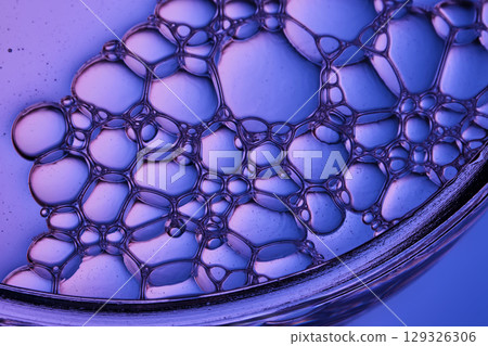 The texture of a cosmetic serum with a trail of bubbles on a purple background. The texture of a cosmetic serum with a trail of bubbles on a purple background. 129326306