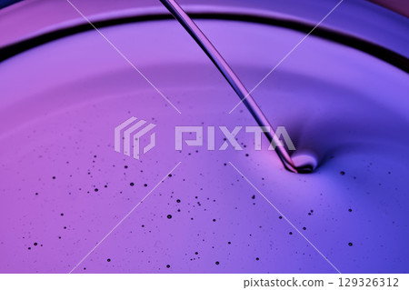 Serum or body cream flows into a petri dish on a purple background. 129326312