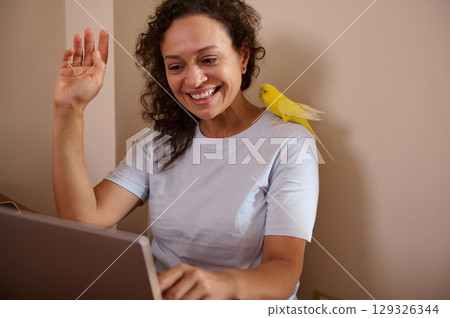 Woman Engaging in Remote Work With a Parrot Companion, Expressing Joy and Connection Woman Engaging in Remote Work With a Parrot Companion, Expressing Joy and Connection 129326344