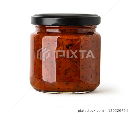 Glass jar filled with red tomato sauce and black lid on white background 129326724