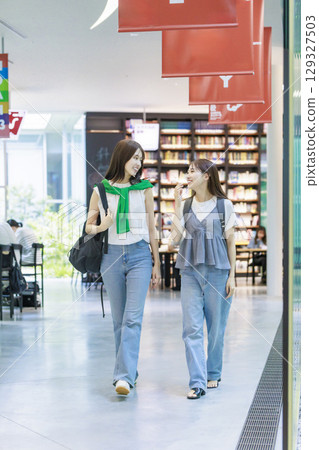 A female college student climbing the stairs on campus with her friends A female college student climbing the stairs on campus with her friends 129327503