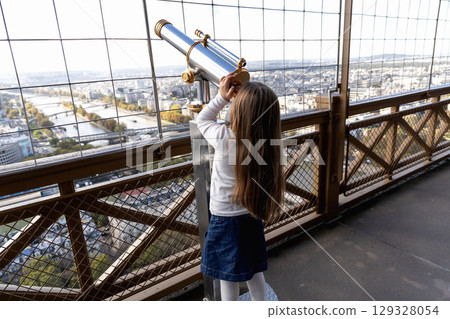 A little girl looks through a large telescope on an observation deck A little girl looks through a large telescope on an observation deck 129328054