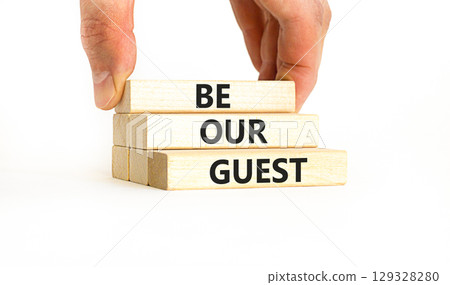 Be our guest symbol. Concept words Be our guest on beautiful wooden block. Businessman's hand. Beautiful white background. Business and be our guest concept. Copy space. 129328280