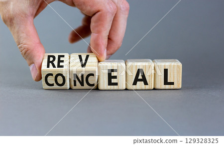 Reveal or conceal symbol. Businessman turns wooden cubes and changes word Conceal to Reveal. Beautiful grey background, copy space. Business reveal or conceal concept. 129328325