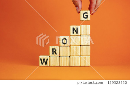 Wrong symbol. Concept word Wrong on beautiful wooden blocks. Beautiful orange table orange background. Businessman hand. Business lifestyle wrong concept. Copy space. 129328330