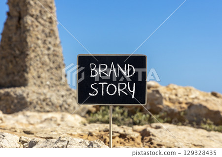 Brand story branding symbol. Concept words Brand story on beautiful yellow chalk blackboard. Beautiful stone beach blue sky background. Business brand story branding concept. Copy space. 129328435